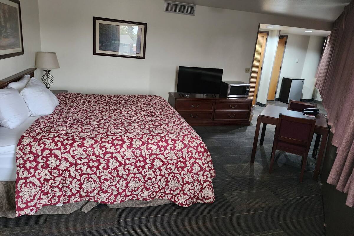 A hotel room with a bed, a TV, a desk, and a chair.