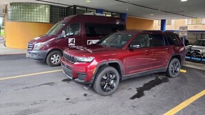 Un parcheggio sotterraneo con un SUV rosso e un furgone, pavimenti in cemento e un muro giallo.