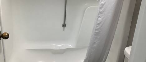 A bathroom with a bathtub, toilet, and shower curtain.