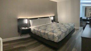 Een moderne hotelkamer met een groot bed, nachtkastjes en een zichtbare badruimte.