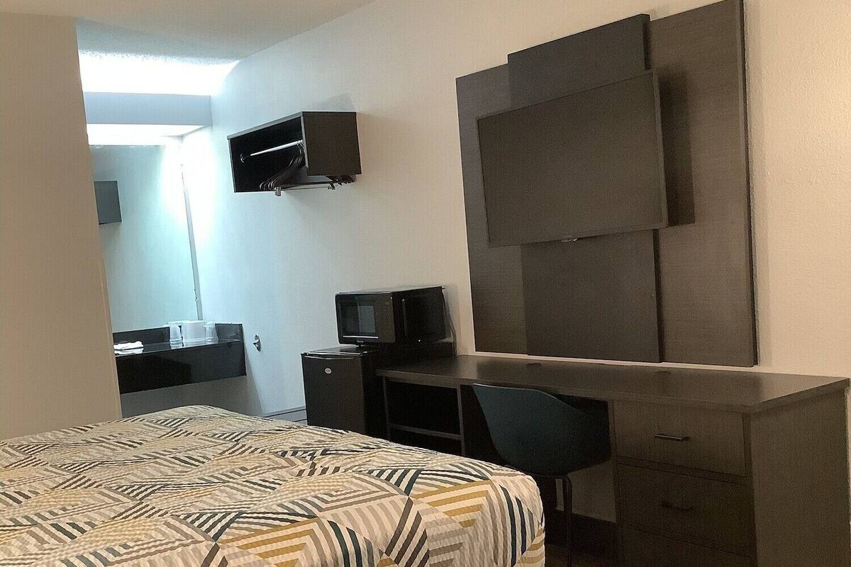 Una habitación de hotel moderna con una cama, un escritorio, un televisor de pantalla plana y un armario.