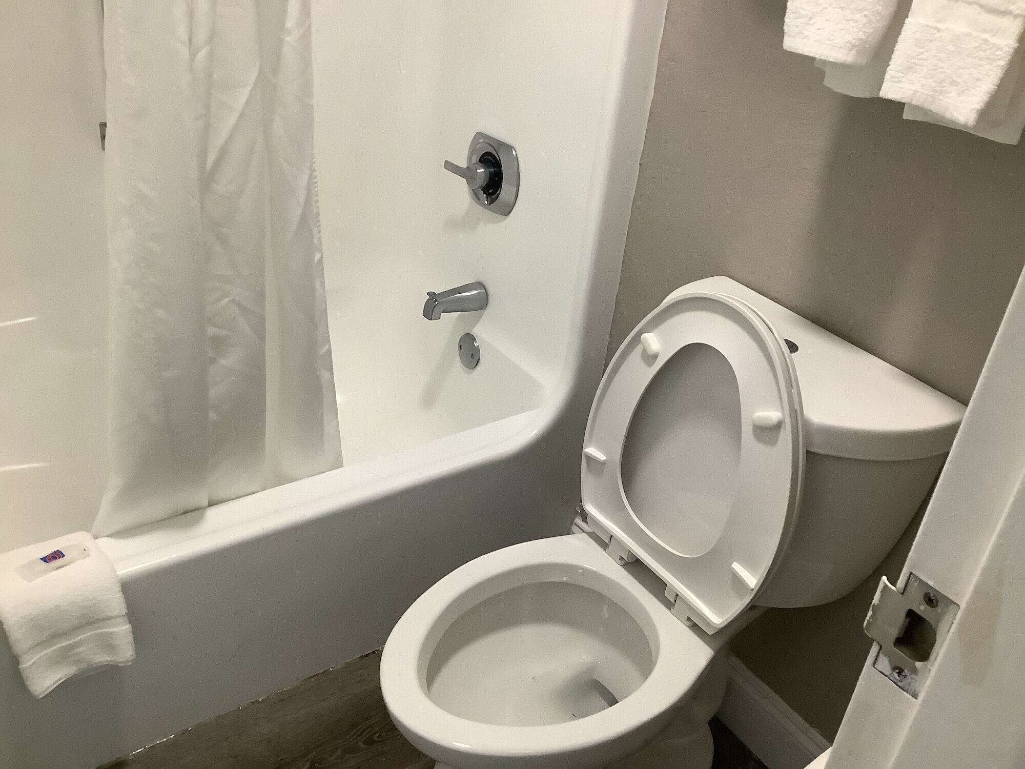 Une salle de bain avec des toilettes blanches, une baignoire et un rideau de douche.