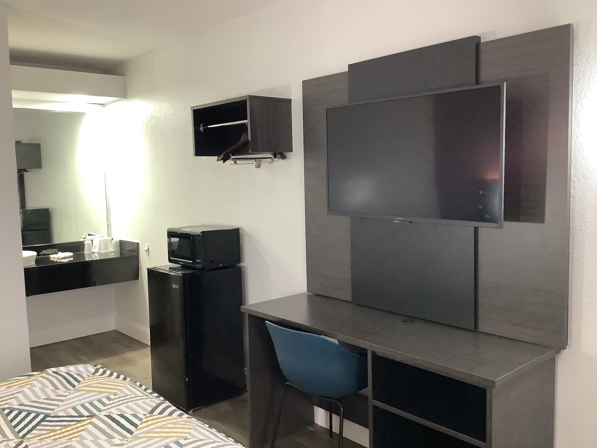 Une chambre d’hôtel équipée d’un lit, d’un bureau avec une chaise, d’une télévision, d’un four à micro-ondes et d’un petit réfrigérateur.