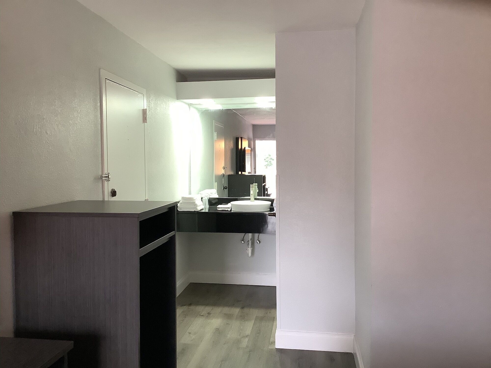 A narrow hallway leading to a bathroom with a white sink and mirror.