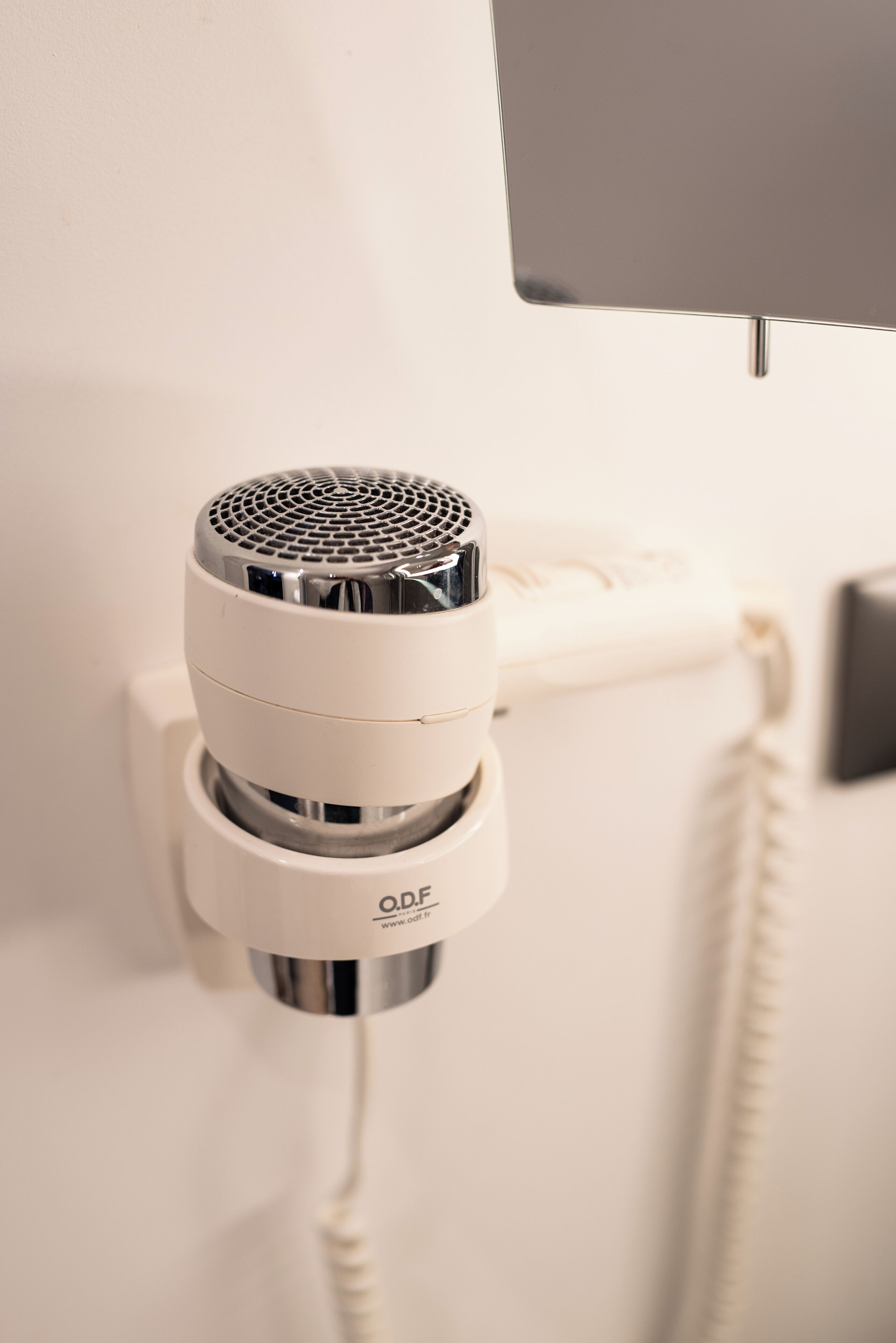 A white telephone with a cord and a metallic device attached to it.