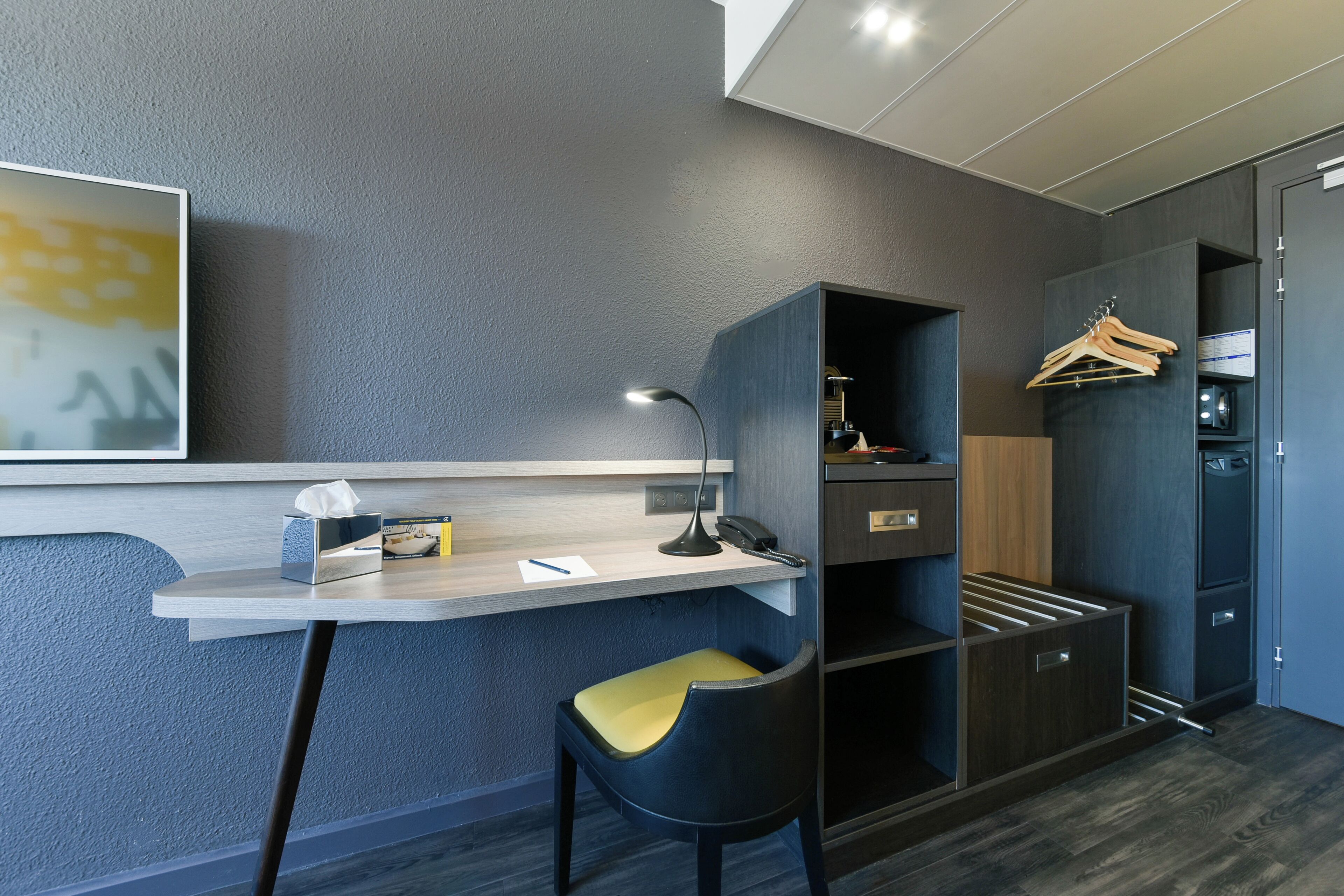 Habitación moderna con escritorio, silla, armario y perchero.