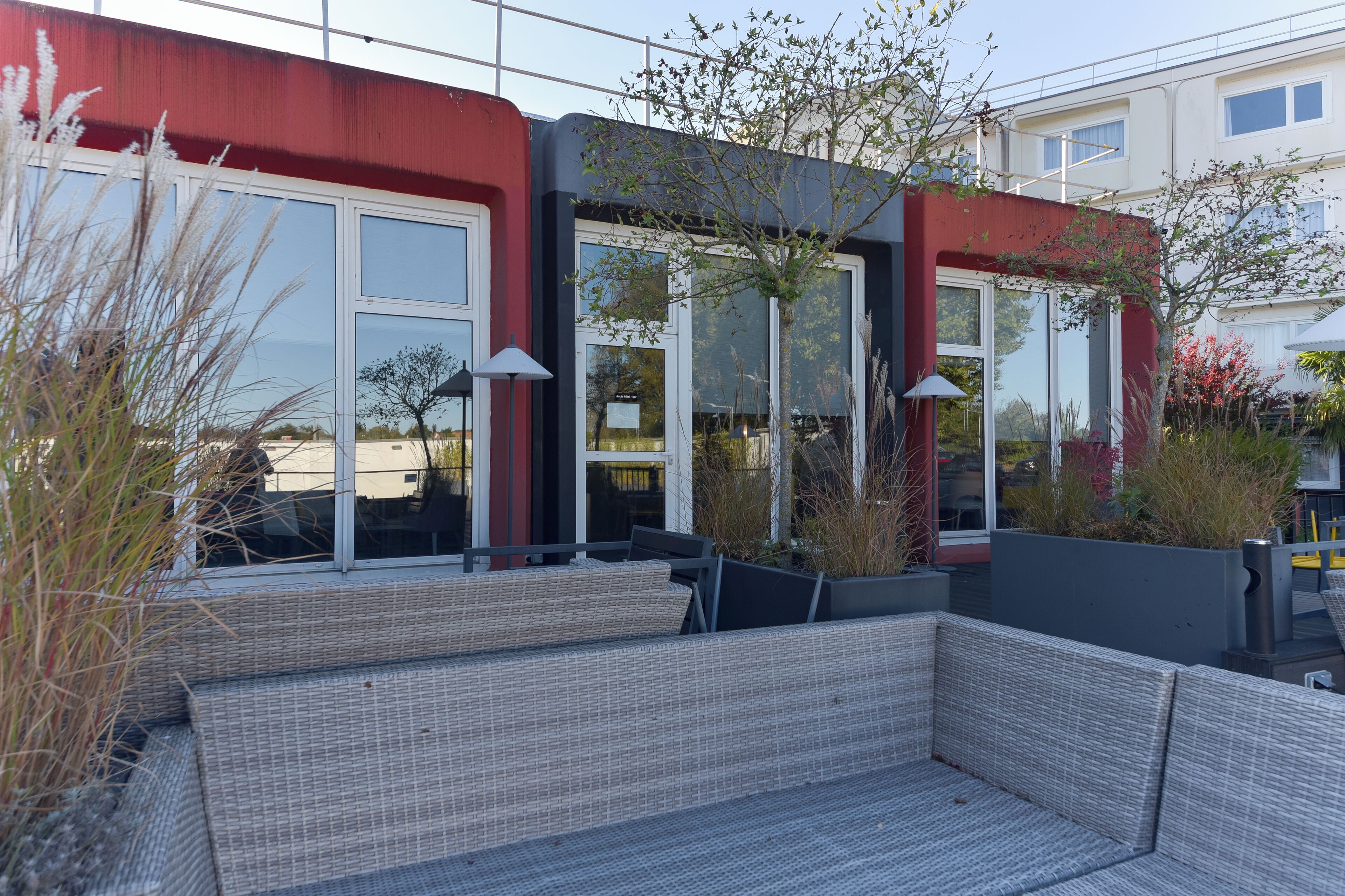 A modern outdoor seating area with wicker furniture and large windows.