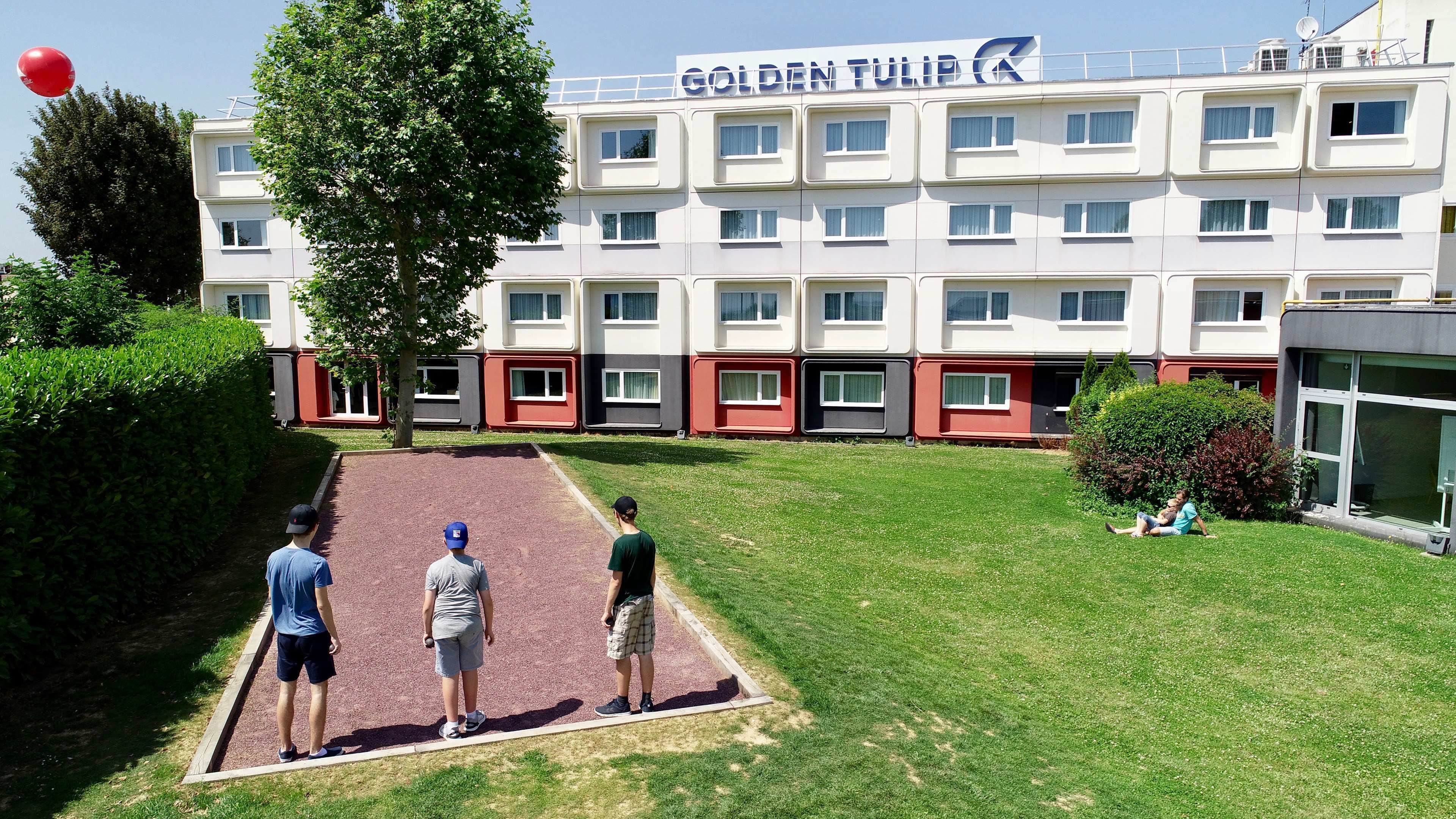 A hotel with multiple floors, a playground area, and a well-maintained lawn.