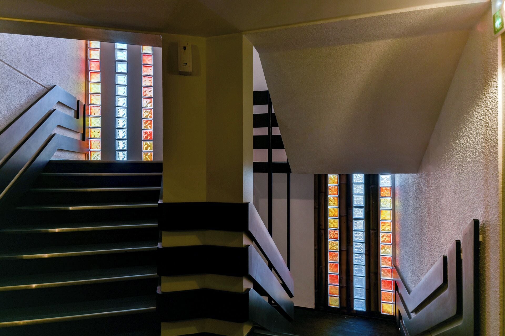 A staircase with black and white striped handrails and stained glass windows.