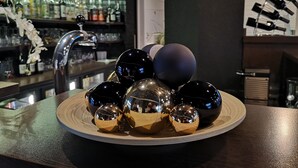 A bar area with a variety of bottles and a decorative arrangement of spherical ornaments on a wooden tray.