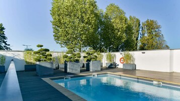 Una piscina al aire libre, sillones reclinables de piscina