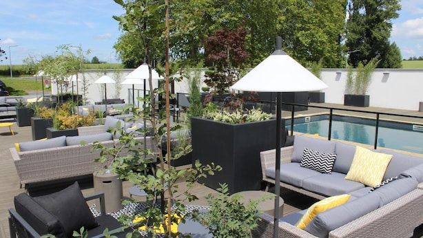 An outdoor seating area with wicker furniture, a pool, and potted plants.