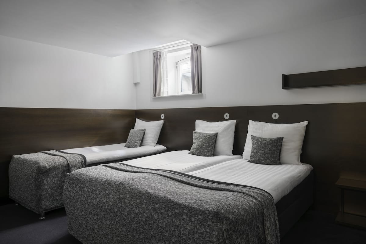 Ein Hotelzimmer mit zwei Betten, einem Fenster mit Vorhängen und einem Nachttisch.