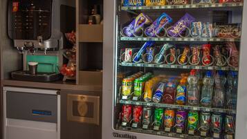 Máquina expendedora con diversas botanas y bebidas, que incluye una máquina de café y un refrigerador con la etiqueta 'Select Ice'.