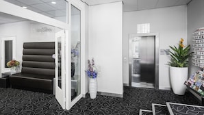 Eine Hotelhalle mit Empfangstresen, einer Sitzecke, einer großen Topfpflanze und einem Wandverzeichnis.
