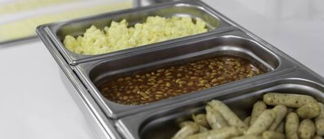 Un bufé con tres fuentes de arroz, frijoles y salchichas.