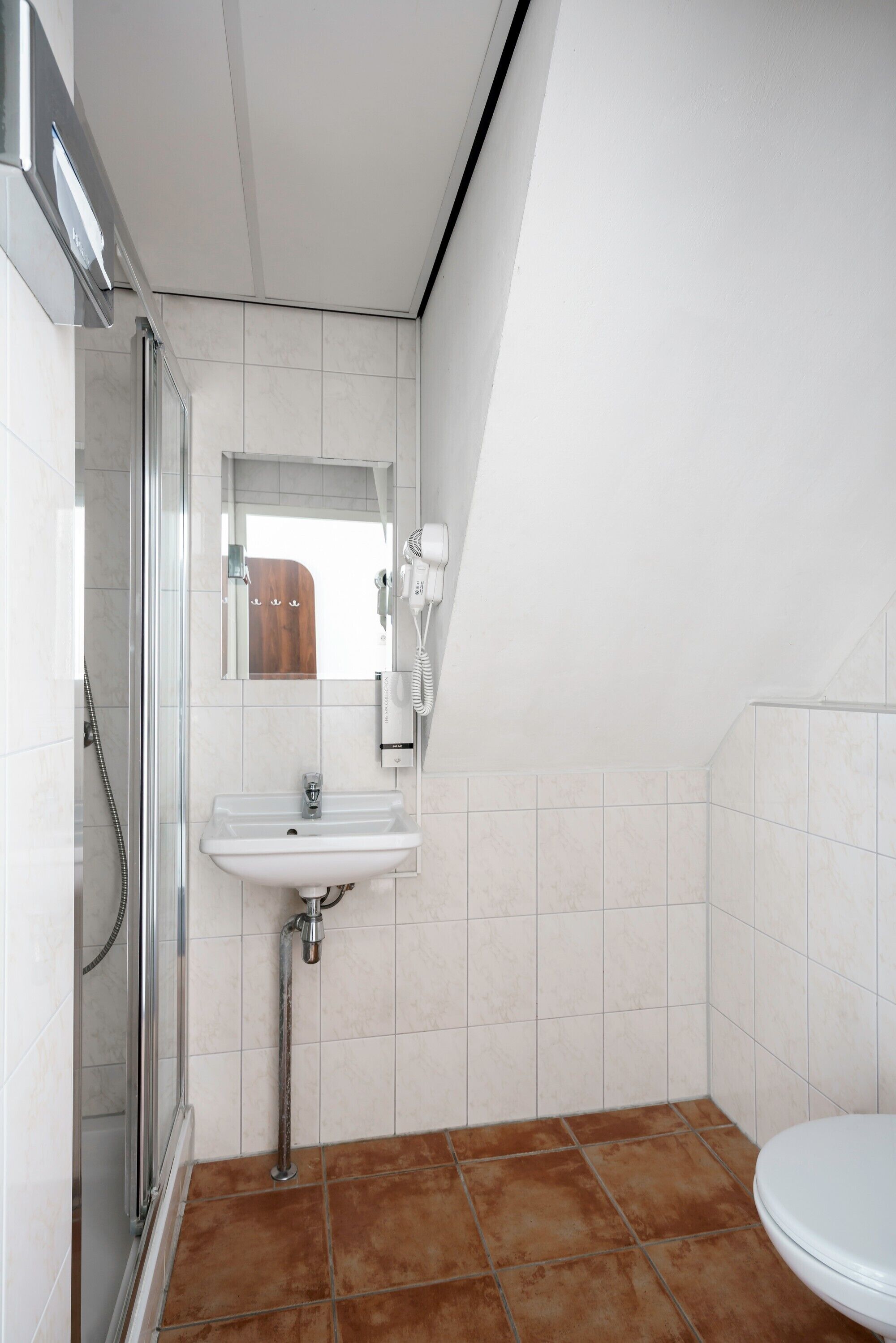 A bathroom with a glass shower enclosure, a white sink, and a toilet.