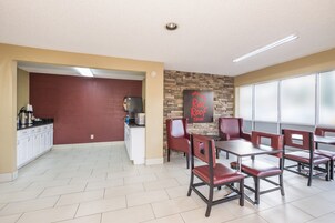 Comedor de Red Roof Inn con pared de acento de ladrillo, armarios blancos y sillas de cuero rojo.