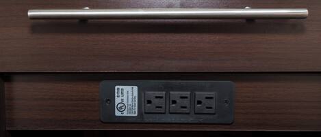 Un cajón con un tirador de metal y una regleta con tres enchufes.