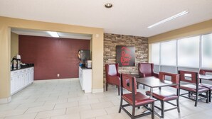 A Red Roof Inn dining area with a brick accent wall, white cabinets, and red leather chairs. - Red Roof Inn Acworth - Emerson/ LakePoint South (Acworth)