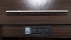 A wooden drawer with a metal handle and a power outlet with a label. - Red Roof Inn Acworth - Emerson/ LakePoint South (Acworth)