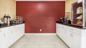 A kitchen with white cabinets, a red accent wall, and various appliances including a coffee maker and a microwave. - Red Roof Inn Acworth - Emerson/ LakePoint South (Acworth)