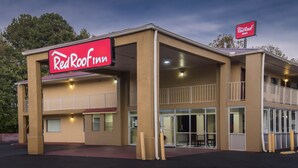 Ein Red Roof Inn mit einer zweistöckigen Bauweise, einer überdachten Einfahrt und einem sichtbaren Balkon im oberen Geschoss.