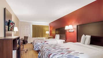 Een hotelkamer met twee bedden, een bureau, een stoel, een televisie en een lamp.