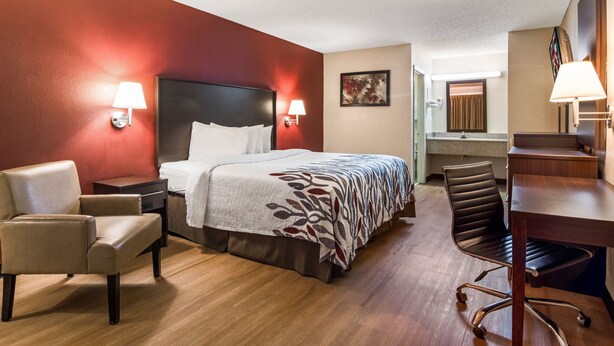 A hotel room with a bed, a desk, a chair, a nightstand, and a lamp. - Red Roof Inn Acworth - Emerson/ LakePoint South (Acworth)