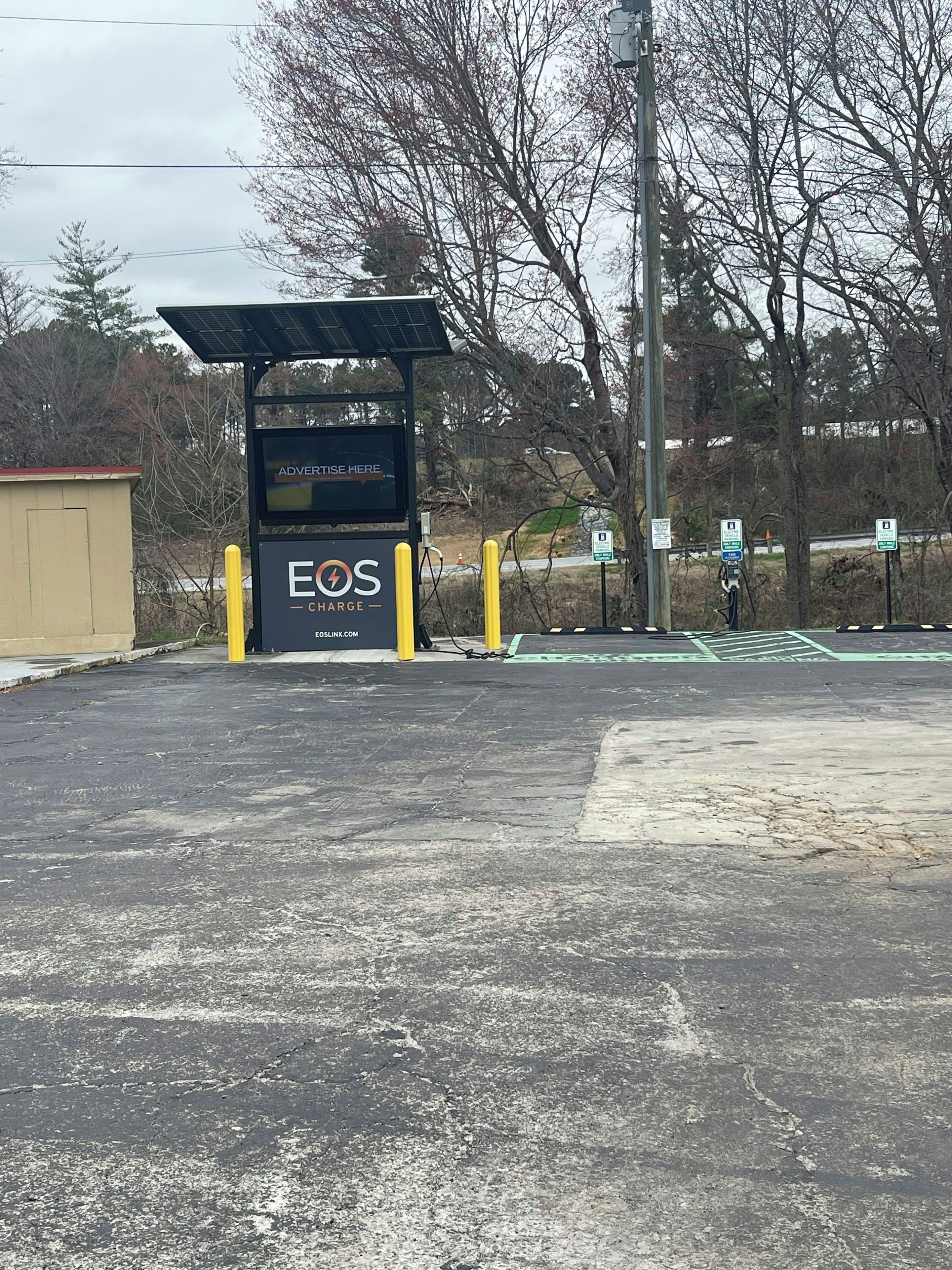 A charging station with a sign that reads 'EOS CHARGE' and a website address.