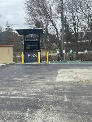 Una estación de carga con un letrero que dice 'EOS CHARGE' y una dirección web.