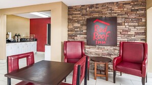 A Red Roof Inn dining area with a brick wall, red leather chairs, and a wooden table. - Red Roof Inn Acworth - Emerson/ LakePoint South (Acworth)