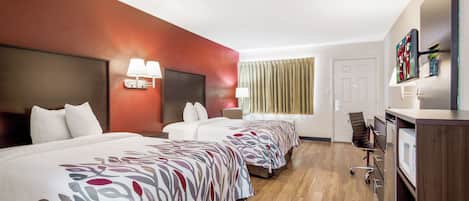 Une chambre d’hôtel avec deux lits, un bureau, une chaise, une télévision et une fenêtre avec des rideaux.