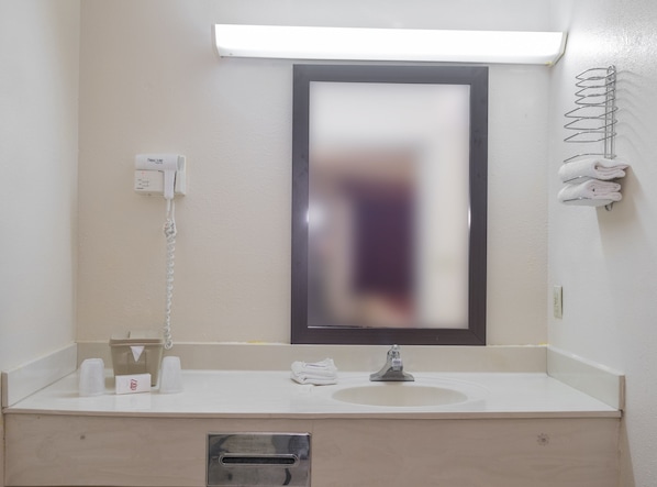 A bathroom with a white sink, a mirror, a towel rack, and a trash bin. - Red Roof Inn Acworth - Emerson/ LakePoint South (Acworth)