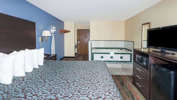 Habitación de hotel con cama, televisión, escritorio y baño visible a través de una puerta abierta.