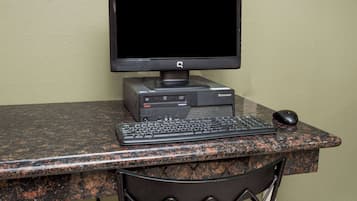 A desktop computer setup with a monitor, keyboard, and mouse on a granite countertop.