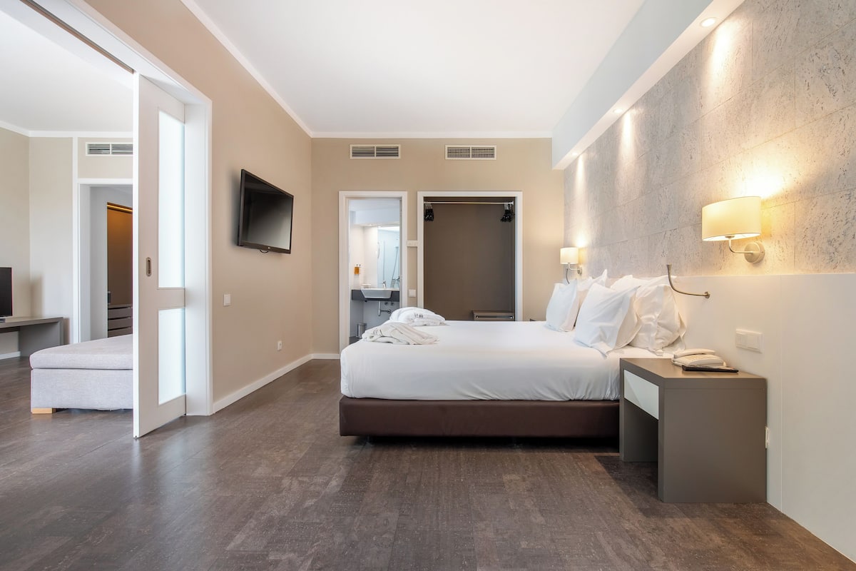 Camera d'albergo con un letto, comodino, televisore e cabina armadio.
