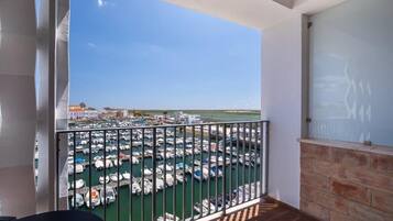 Un balcón con vista a un puerto deportivo y edificios a lo lejos.