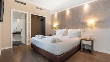 A modern hotel room with a large bed, bedside tables, and a walk-in closet.