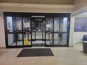 A hotel entrance with a wet floor sign, a mat, and a view of the outside. - Comfort Inn Fayetteville near Fort Bragg (Fayetteville)