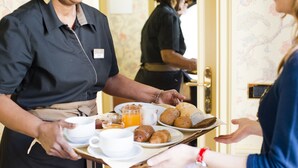 Un miembro del personal del hotel sirve desayuno a un huésped.
