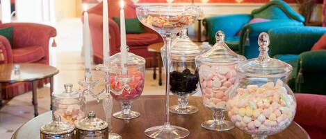 A table with various candy jars and a lit candle.