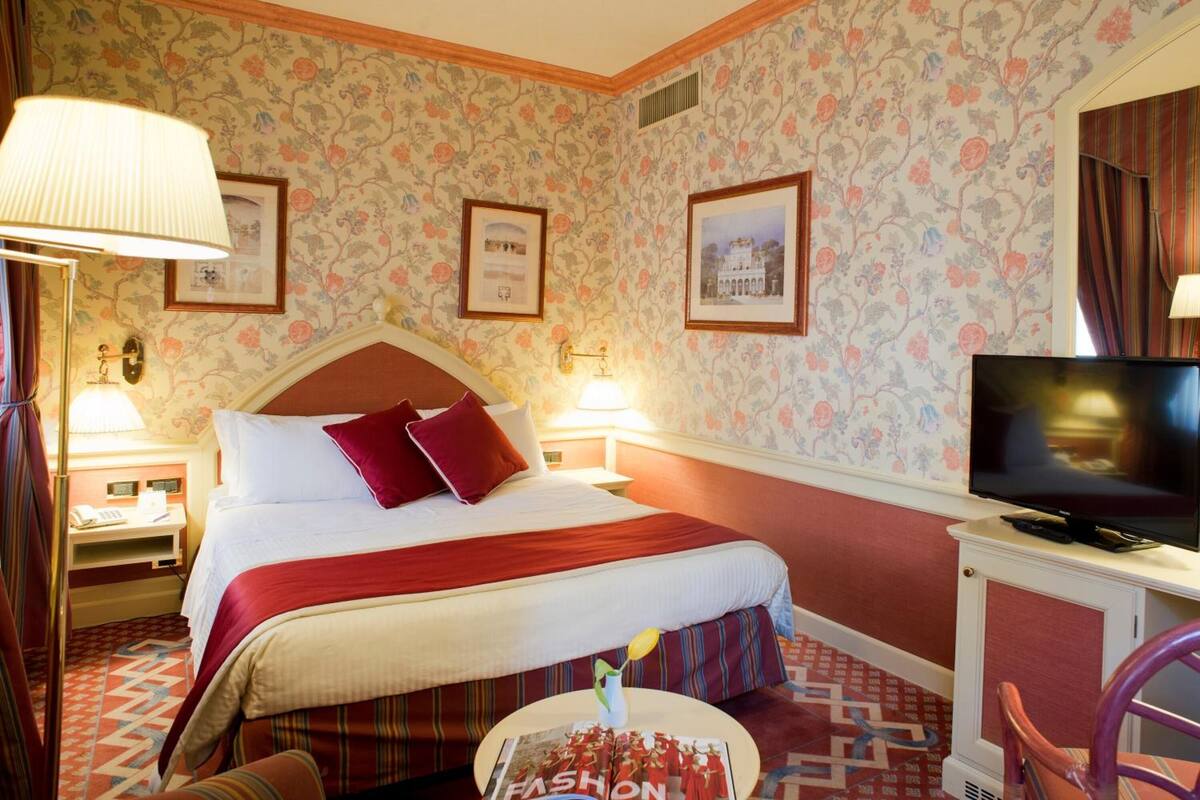 Ein Hotelzimmer mit einem großen Bett, einem Fernseher, einem Schreibtisch und einem Sessel.