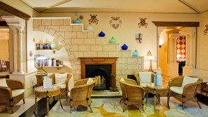 Un hall con mobiliario de mimbre, una chimenea y decoración en las paredes.