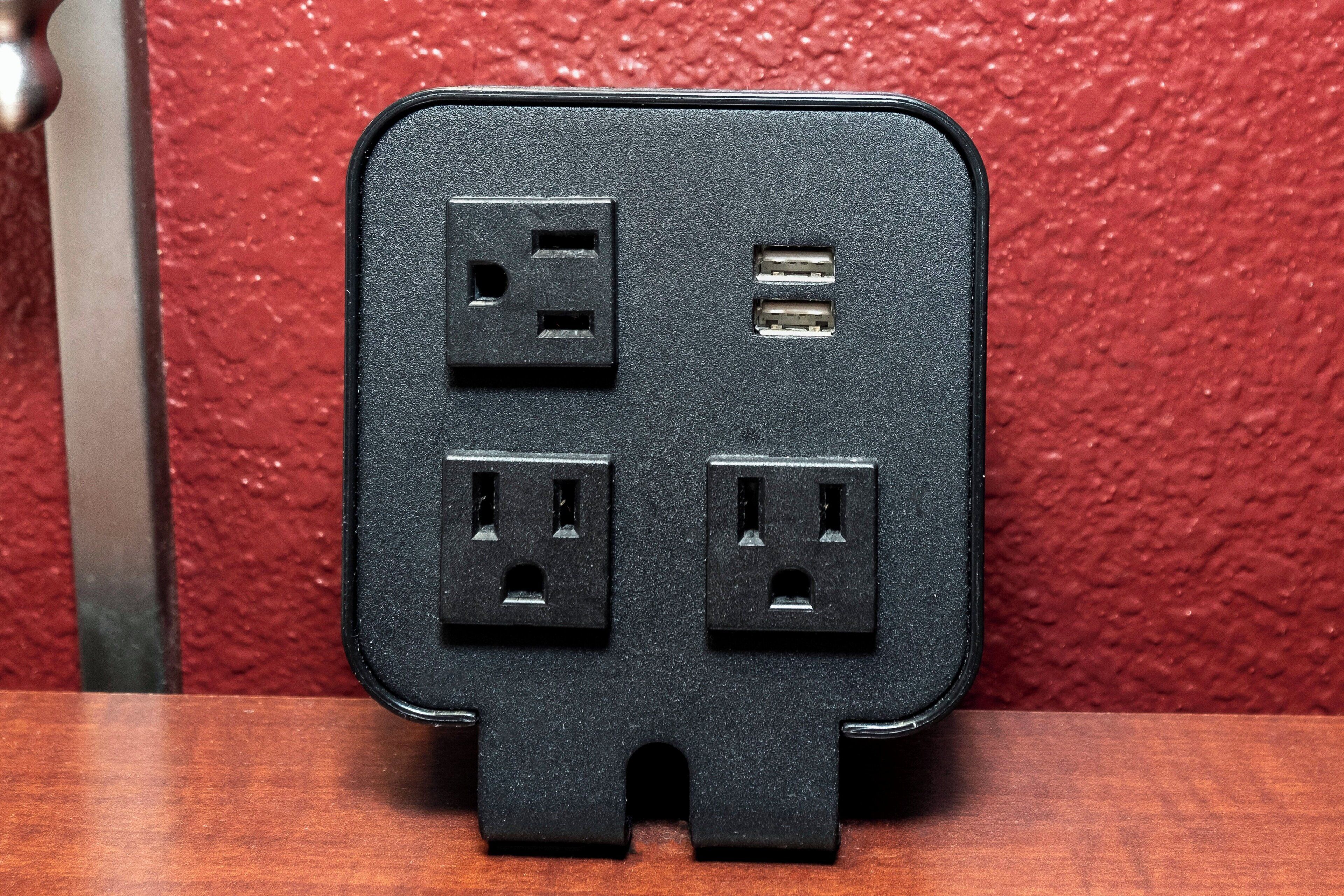 A black power strip with three outlets and two USB ports.
