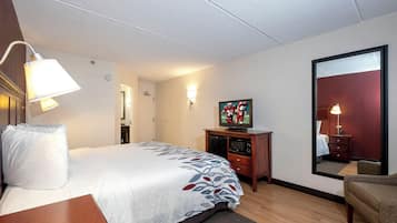 A hotel room with a bed, a television, a desk, and a mirror.