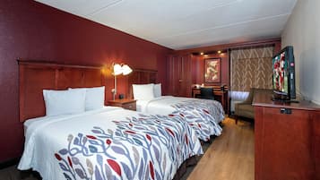 A hotel room with two beds, a desk, a TV, and a chair.