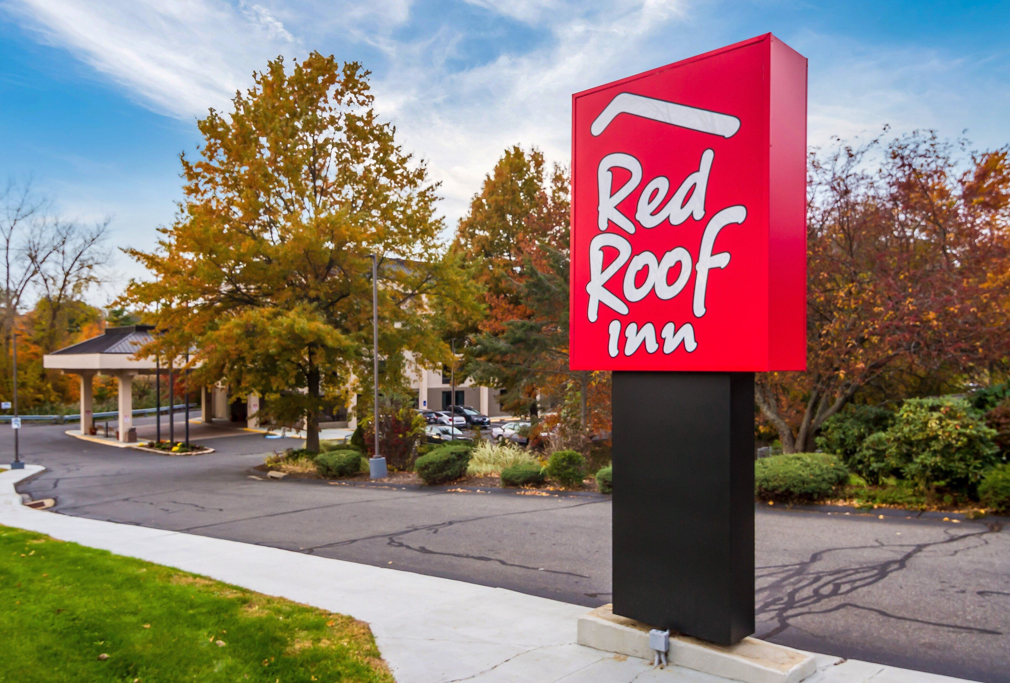 A Red Roof Inn sign with a clear view of the parking lot and surrounding trees.