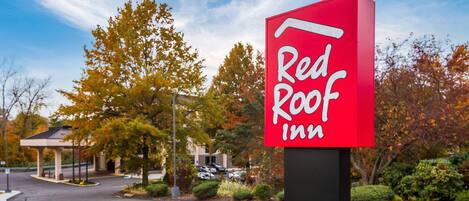 A Red Roof Inn sign with a clear view of the parking lot and surrounding trees.