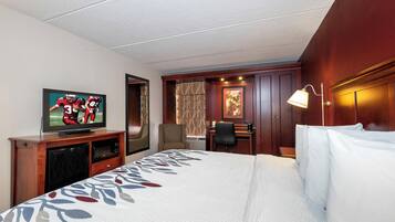 A hotel room with a bed, a television, a desk, and a chair.